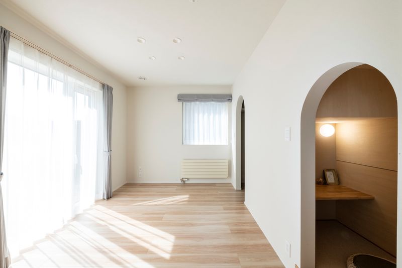 大きな窓から光が入る続き間の洋室。アーチ型の開口の先にカウンターのあるヌック（住研ハウスの施工事例）